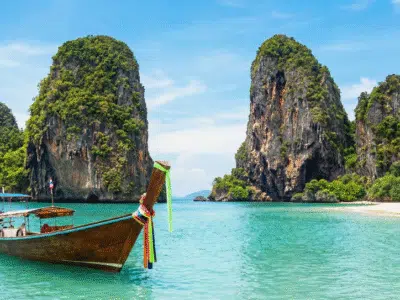 Houten longtailboot op een tropisch Thais strand met helder water; illustratie voor de gids over de veiligheid van kraanwater in Thailand.